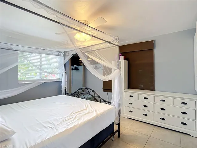 Bedroom featuring a window with blinds, tile flooring, and a ceiling fan with integrated lighting
