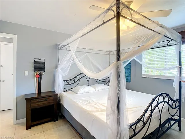 Bedroom featuring tiled flooring, a ceiling fan with integrated lighting, and a window with horizontal blinds