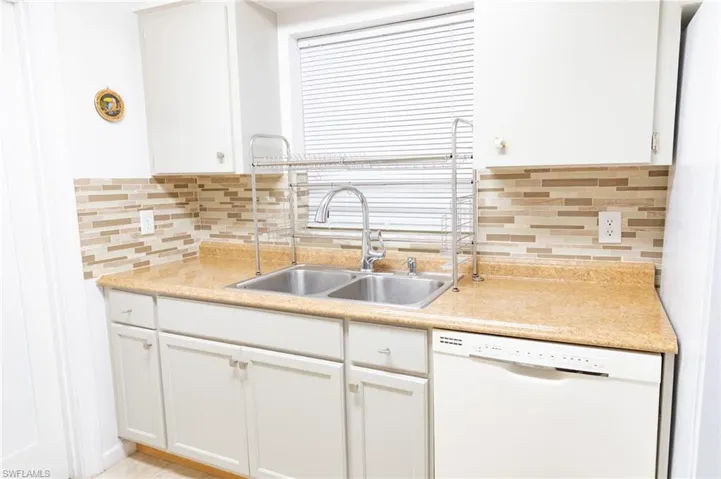 Kitchen with dishwasher, light countertops, and white cabinetry