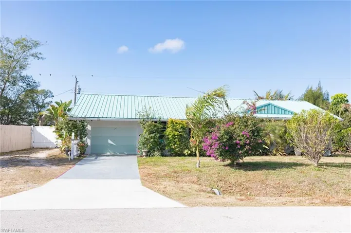 View of front of property with concrete driveway, a metal roof, a garage, and stucco siding
