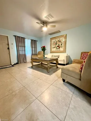 Living area with light tile patterned flooring and ceiling fan