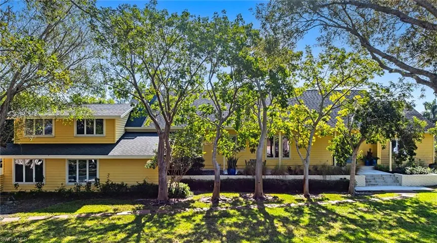 Back of property featuring a yard and a shingled roof