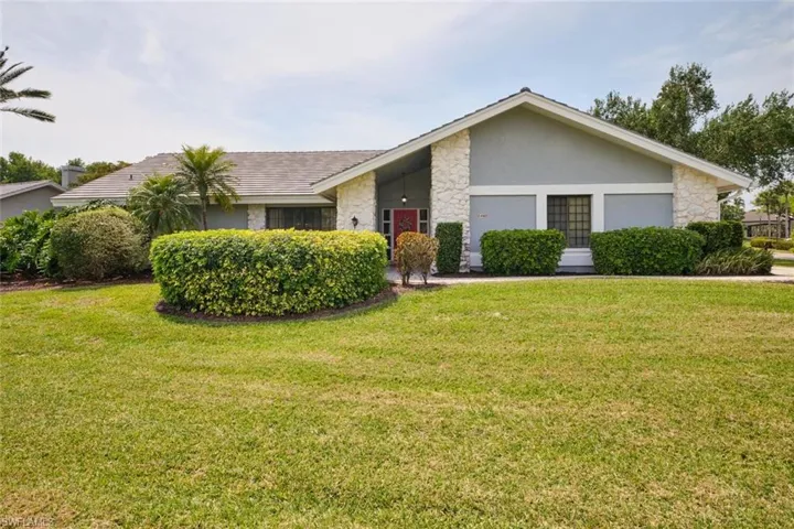 View of front of property with a large front yard, stone and stucco siding.
