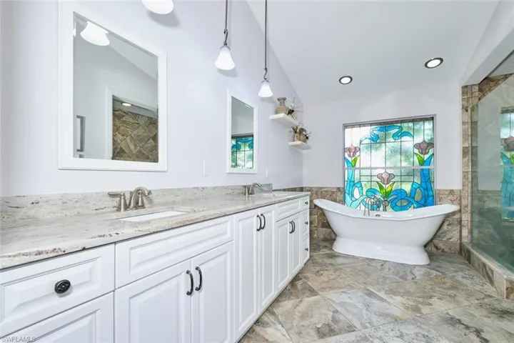 Full bath with tile floors, a soaking tub, double vanity, custom stained glass window and tiled shower.