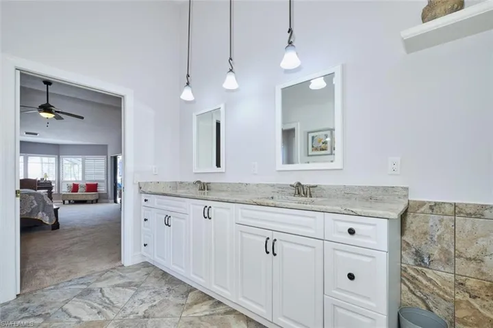 Ensuite bathroom featuring double vanity, pendant lighting, and wall tile feature.