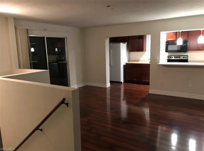Kitchen featuring black appliances, dark wood-type flooring, light countertops, a peninsula, and hanging light fixtures