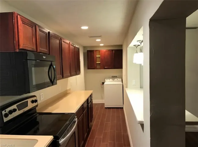 Kitchen featuring electric range, washer / dryer, black microwave, light countertops, and recessed lighting