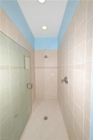 Spa-like en-suite bath features dual Corian vanities with large mirrors, soaking tub, walk-in shower with frameless glass, upgraded tile, and shampoo niche, recessed lighting, linen closet, and a private water closet.