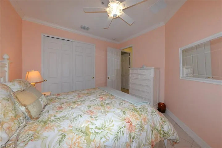 Spacious Guest bedroom features tile flooring, crown molding, ample closet space, ceiling fan with light kit and window blinds.