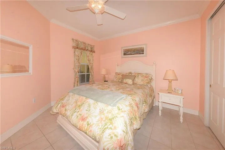 Spacious Guest bedroom features tile flooring, crown molding, ample closet space, ceiling fan with light kit and window blinds.