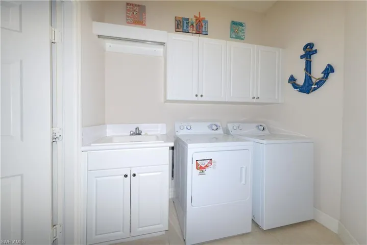 Laundry room with washer, dryer, laundry sink and cabinetry.