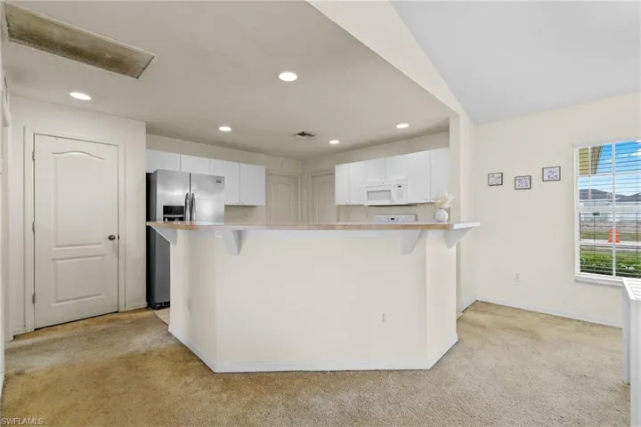 Kitchen featuring appliances with stainless steel finishes, light tile patterned floors, white cabinetry, recessed lighting, and light countertops