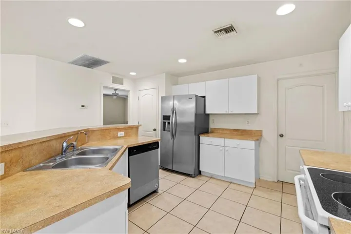Kitchen with white appliances, recessed lighting, light countertops, and white cabinetry