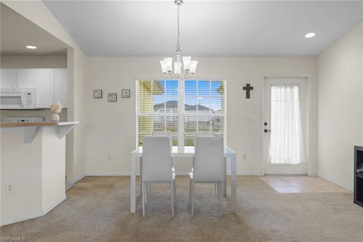 Kitchen with white appliances, lofted ceiling, a chandelier, white cabinets, and recessed lighting