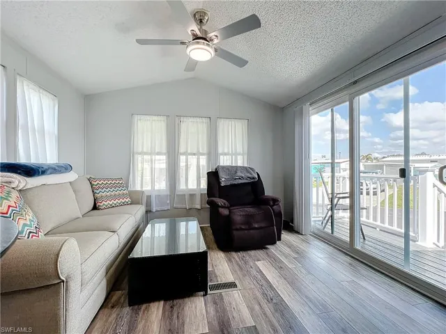 Living area with wood finished floors, lofted ceiling, a textured ceiling, and a ceiling fan