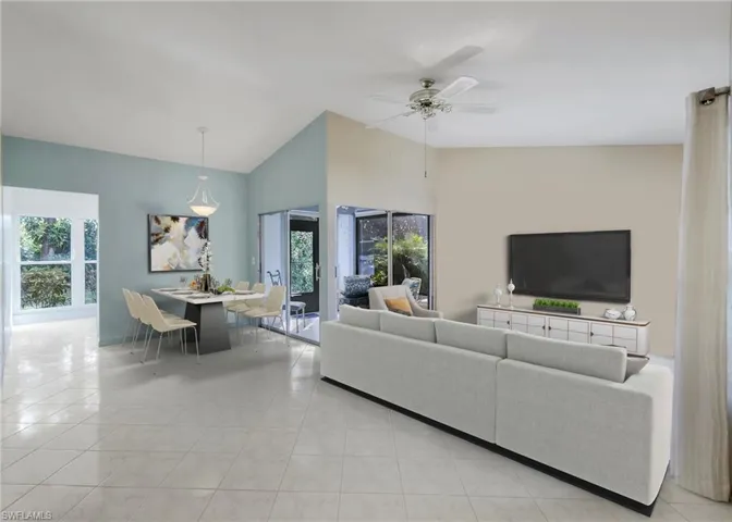 Staged living room staged with ceiling fan and lofted ceiling