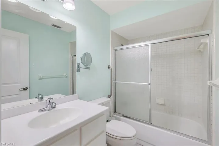 Full bathroom with vanity, toilet, and bath / shower combo with glass door