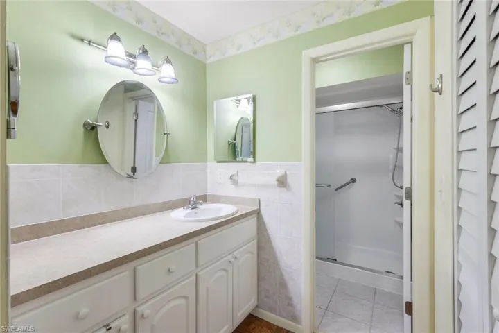 Bathroom with tile patterned flooring, vanity, an enclosed shower, and tile walls