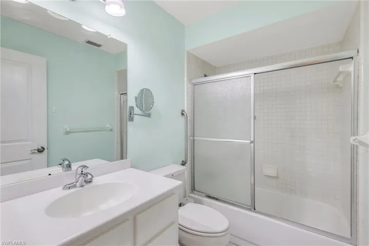 Full bathroom featuring shower / bath combination with glass door, vanity, and toilet