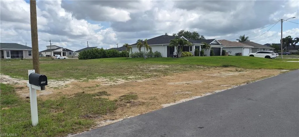 Expansive undeveloped lot featuring street frontage, a mailbox, and surrounding residential properties