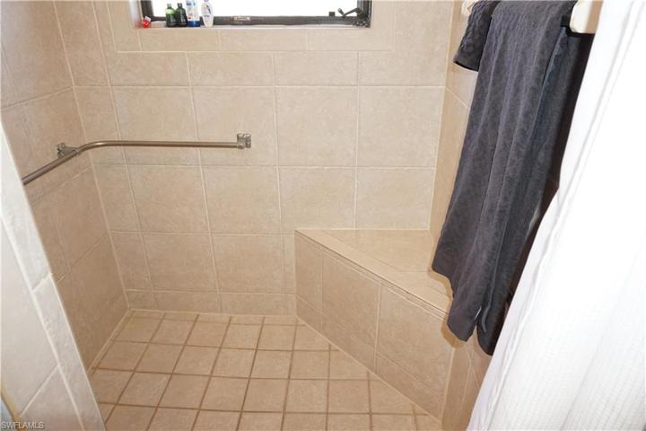 Guest shower equipped with ADA grab bars and seat bench