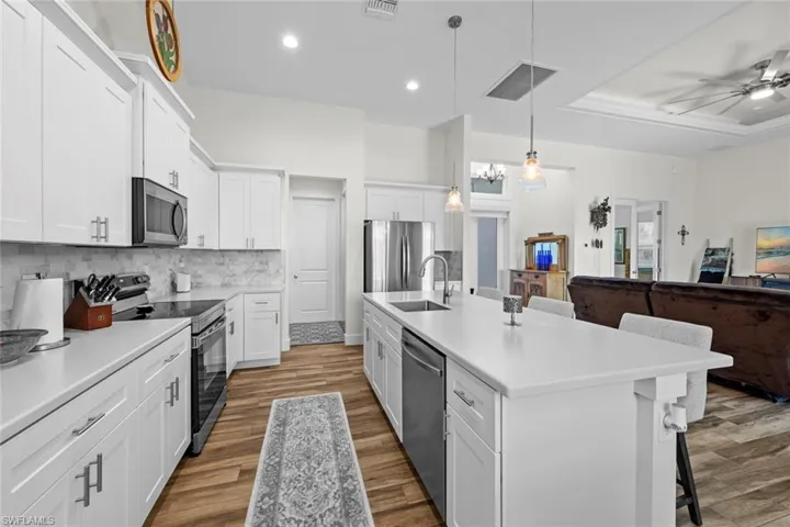 Kitchen featuring a kitchen bar, appliances with stainless steel finishes, sink, a center island with sink, and white cabinetry