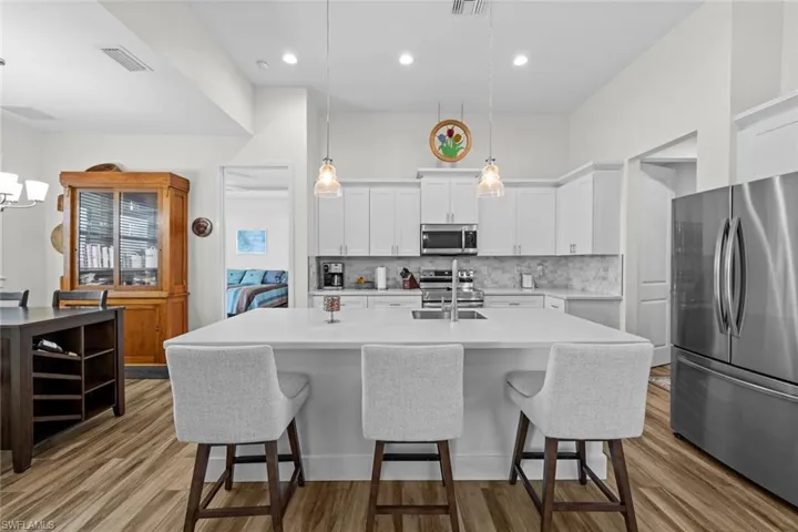 Kitchen featuring pendant lighting, white cabinetry, an island with sink, and appliances with stainless steel finishes