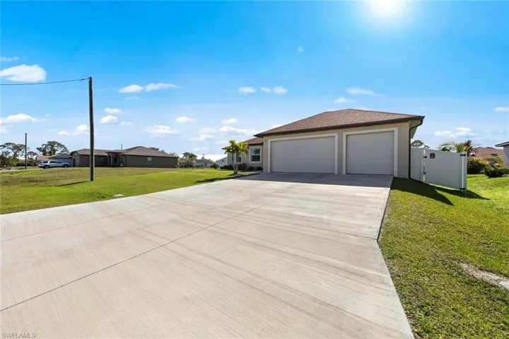View of side of property featuring a lawn and the 3-car garage