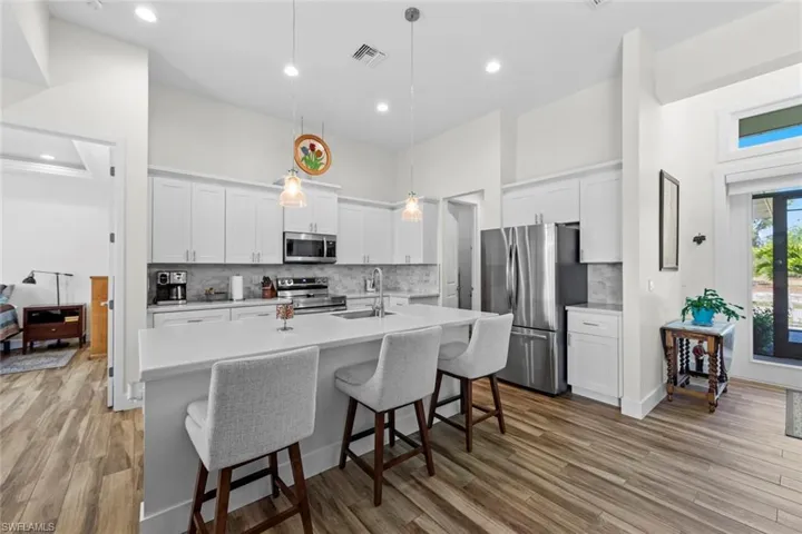 Kitchen featuring white cabinets, sink, stainless steel appliances, and hanging light fixtures