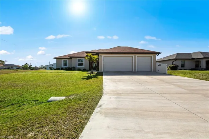 View of side of property featuring a lawn and the 3-car garage