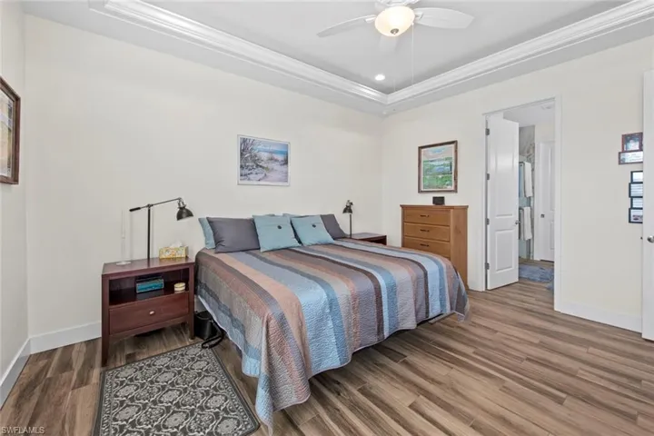 Bedroom featuring a raised ceiling, ceiling fan, hardwood / wood-style floors, and crown molding