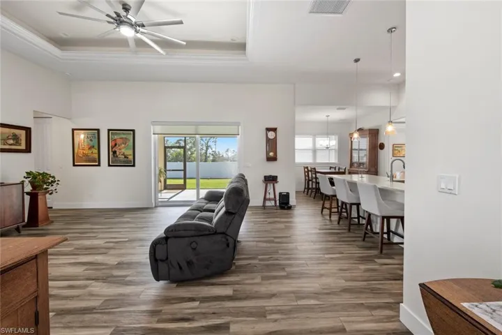 Living room with hardwood / wood-style floors, a tray ceiling, and a healthy amount of sunlight
