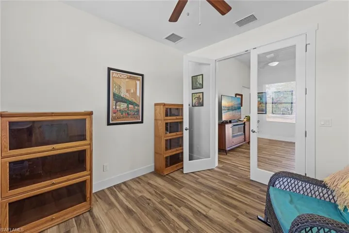 Front Den with glass doors featuring hardwood / wood-style floors and ceiling fan