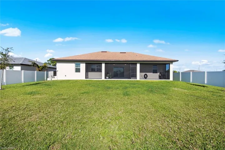 Rear view of house featuring a lanai and a yard