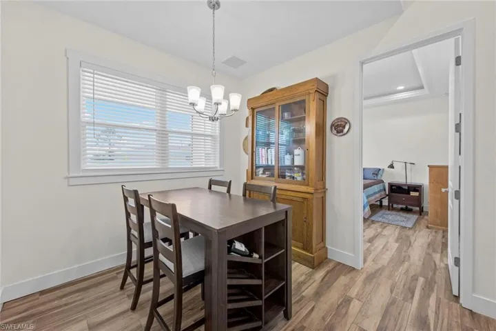 Dining space featuring wood-type flooring, a tray ceiling, and an inviting chandelier