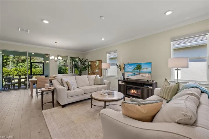 Living room with crown molding, a notable chandelier, and light wood-type flooring