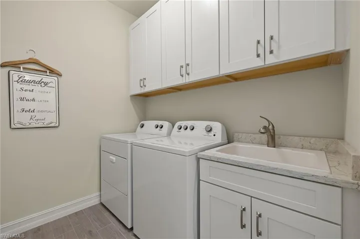 Washroom with sink, cabinets, and washing machine and clothes dryer