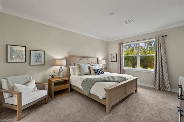 Primary bedroom with ornamental molding and light carpet