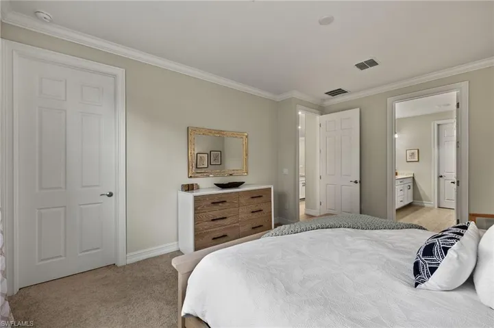 Carpeted bedroom with crown molding and ensuite bathroom