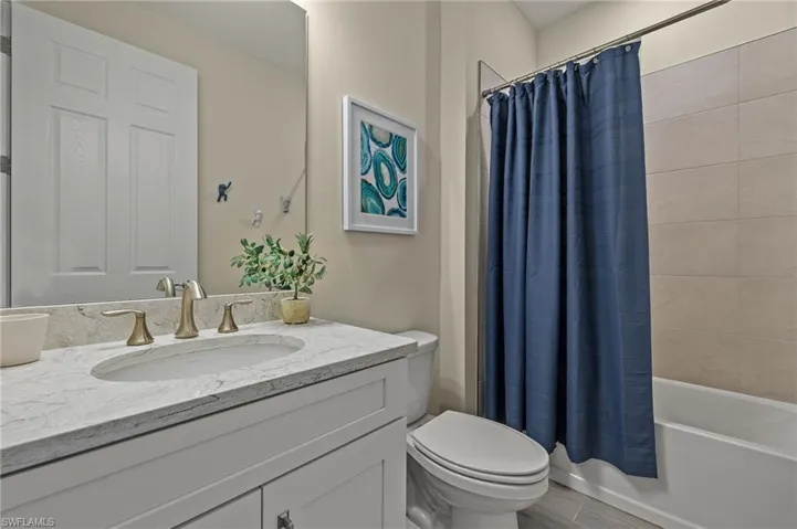 Full bathroom with hardwood / wood-style flooring, vanity, toilet, and shower / bath combo with shower curtain