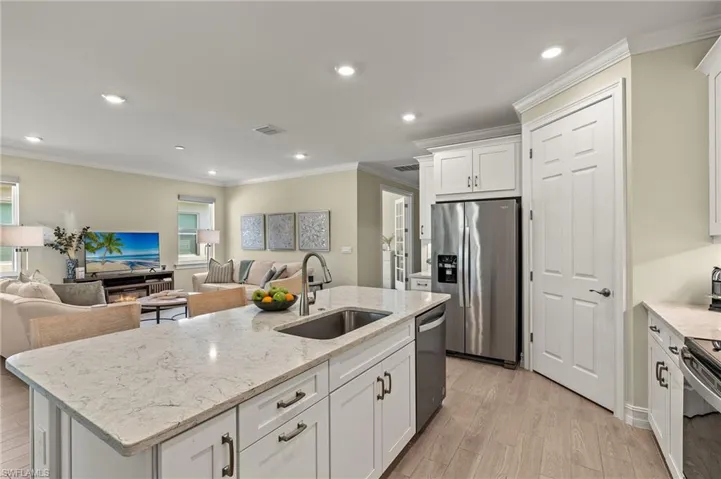 Kitchen featuring stainless steel appliances, white cabinetry, sink, and a kitchen island with sink