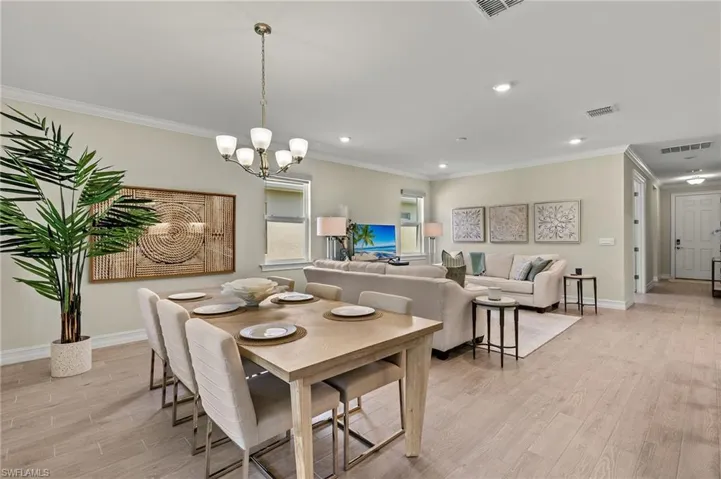 Dining area featuring crown molding, a notable chandelier, and light wood-type flooring