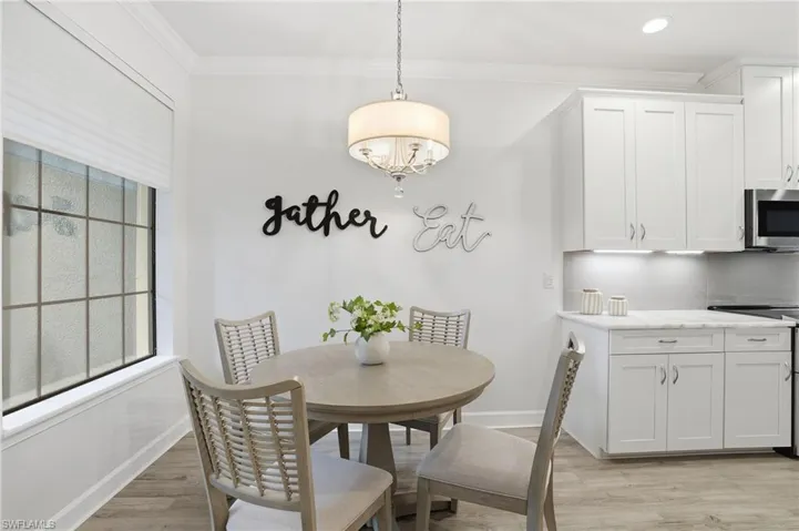 Dining room with light wood-type flooring, crown molding, and a chandelier