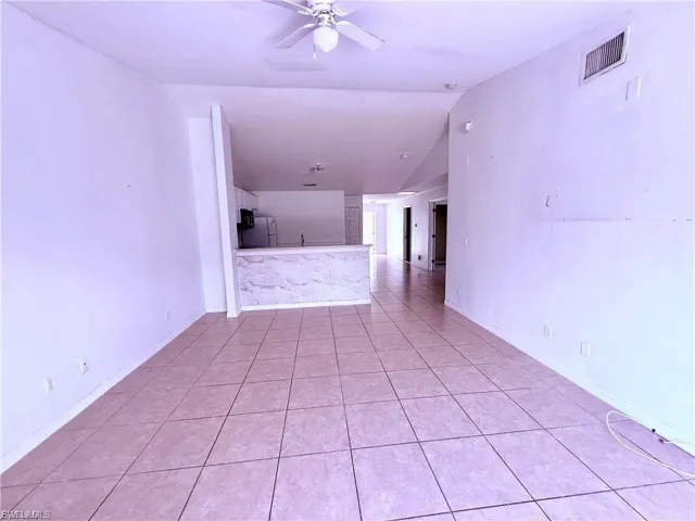Spare room featuring lofted ceiling, light tile patterned flooring, and a ceiling fan