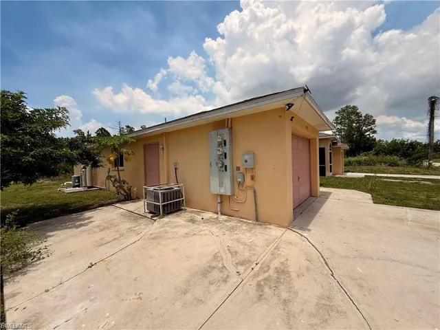 View of side of home with stucco siding, concrete driveway, an attached garage, a patio, and a lawn