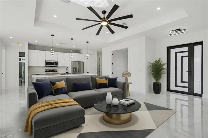 Living area featuring a raised ceiling, ceiling fan, and recessed lighting