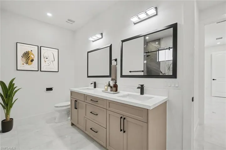 Full bathroom with double vanity, a marble finish shower, and recessed lighting