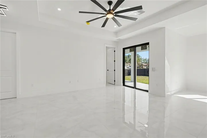 Open-concept living area with tray ceiling and ceiling fan