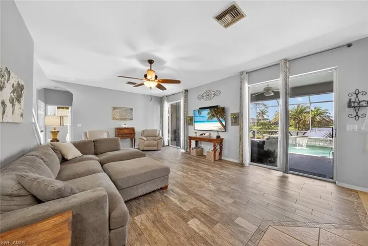 Family room with a ceiling fan, tile floors, plenty of natural light, and arched walkways