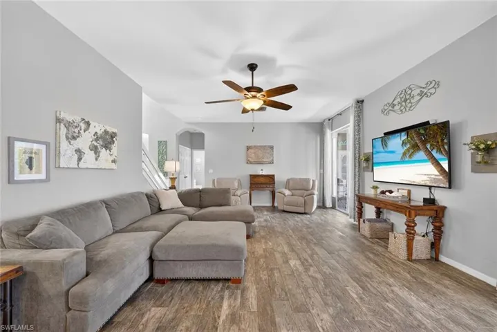 Family room with a ceiling fan, arched walkways, and tile floors